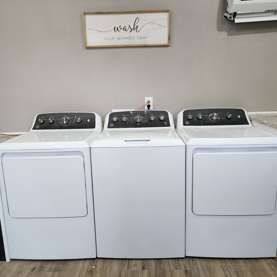 Interior of the complimentary laundry room with three washers and dryers